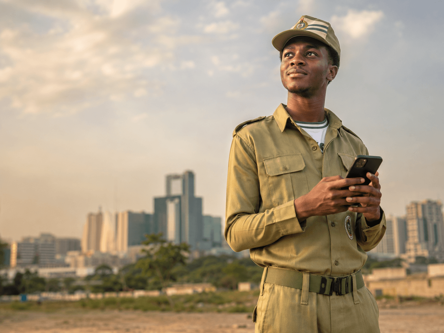 A young Nigerian graduate looking at her phone with a hopeful expression